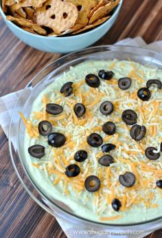 an appetizer with cheese, olives and tortilla chips in a bowl