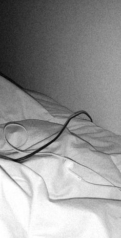 a black and white photo of a hair dryer laying on a bed with sheets