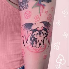 a woman with a cat and dragon tattoo on her arm, next to a pink wall