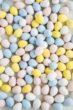 several different colored candy eggs on a white surface with yellow and blue speckles