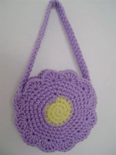 a crocheted purse hanging on the wall with a yellow circle in the center