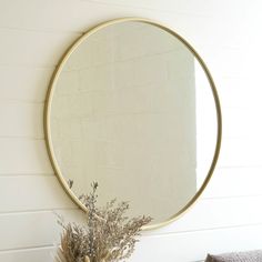 a round mirror sitting on top of a wooden table next to a vase filled with flowers