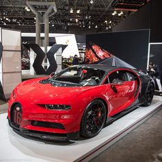 a red bugatti car on display at an auto show with people around it