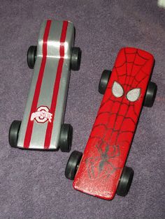 two toy skateboards with spider - man designs on them, one red and the other silver