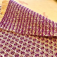 a purple and white blanket laying on top of a wooden table