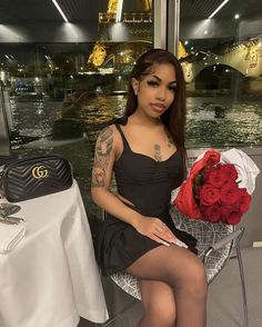 a woman sitting in a chair holding a bouquet of roses and posing for the camera