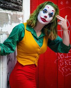 a woman dressed as the joker posing for a photo in front of a red door