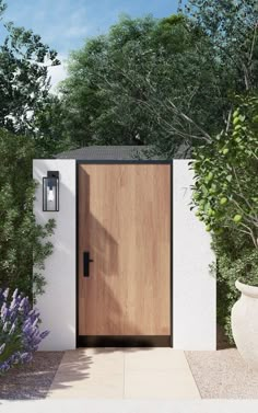 a modern wooden door in front of a white wall and trees with purple flowers on the side