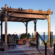 a wooden gazebo sitting on top of a wooden deck next to the ocean with chairs under it