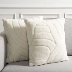 two white pillows sitting on top of a couch