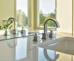 two faucets are sitting on the counter in front of a large window,