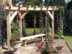 a wooden bench sitting in the middle of a garden next to a flower potted plant