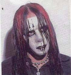 a man with long hair and makeup painted to look like it has blood on his face