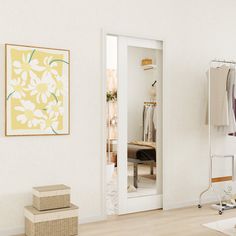 an open closet with clothes on hangers and boxes in the foreground, next to a white wall