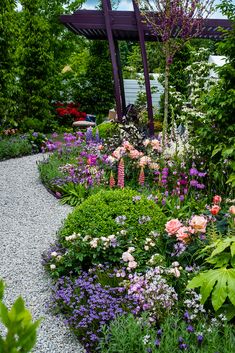 a garden filled with lots of flowers next to a pergolated arbor covered in greenery