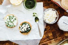 some food is sitting on top of a cutting board and next to other items that include bread