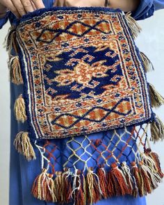 a woman is holding up a blue and orange rug with tassels on it