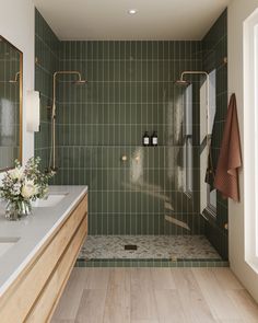 a green tiled bathroom with two sinks and a walk in shower next to a window