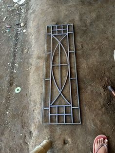 a person standing next to a metal grate on top of a dirt ground with other items around it