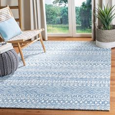 a living room area with a blue rug and wooden chairs in front of a sliding glass door