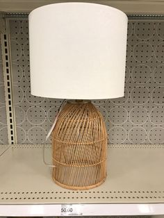 a wicker lamp sitting on top of a shelf next to a white lampshade