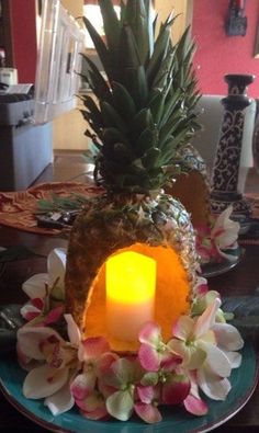 a pineapple shaped candle holder with flowers and candles on the table in front of it