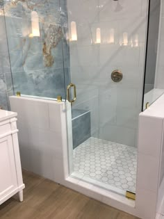 a walk in shower sitting next to a white sink and toilet on top of a hard wood floor