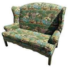 an upholstered couch with a forest scene on the back and green, multicolored fabric