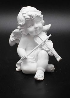 an angel figurine holding a violin on a black background