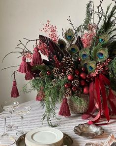 a table set for christmas with peacocks and pine cones