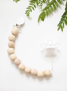 a necklace made out of wooden beads next to a glass cup and green leaves on a white background