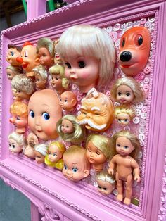 there is a pink frame with many dolls on the front and sides, as well as an image of a child's head