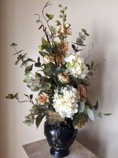 a vase filled with lots of flowers on top of a marble table next to a wall