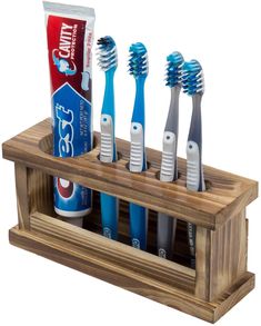 four toothbrushes in a wooden holder with toothpaste and toothpaste