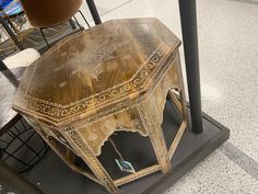 an old wooden table sitting on top of a black stand in front of some chairs