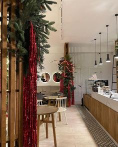 the inside of a restaurant decorated for christmas with red tinsel and greenery hanging from the ceiling