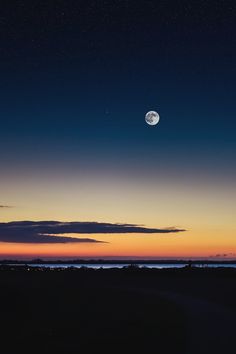 the full moon is seen in the sky above the ocean at night with stars and clouds