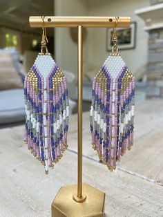 a pair of beaded earrings on a stand in front of a house with a couch