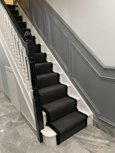 a staircase with black and white carpeting next to a gray stair case on the wall