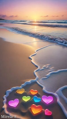 the sun is setting on the beach with hearts in the sand