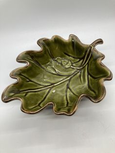 a green leaf shaped bowl on a white surface