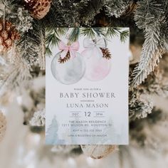 a baby shower card hanging from a christmas tree with pine cones and ornaments around it