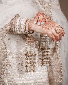 a close up of a person wearing a wedding dress and holding hands with jewelry on it