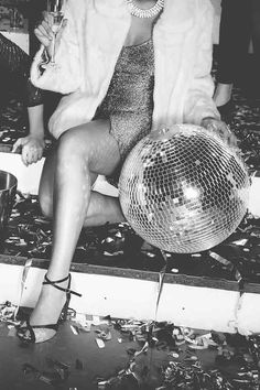 a woman sitting on top of a chair next to a disco ball