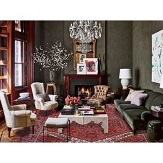 a living room filled with furniture and a chandelier hanging from the ceiling over a fire place