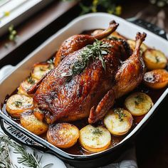 a roasted chicken with potatoes and herbs in a pan