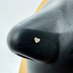 a black mannequin head with a gold and white diamond heart pin on it