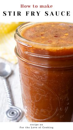 a jar filled with stir fry sauce on top of a white table cloth next to a spoon