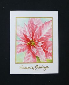 a card with a pink flower on the front and gold lettering that says season's greetings