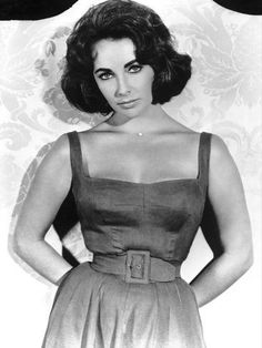 a black and white photo of a woman in a dress with her hands on her hips